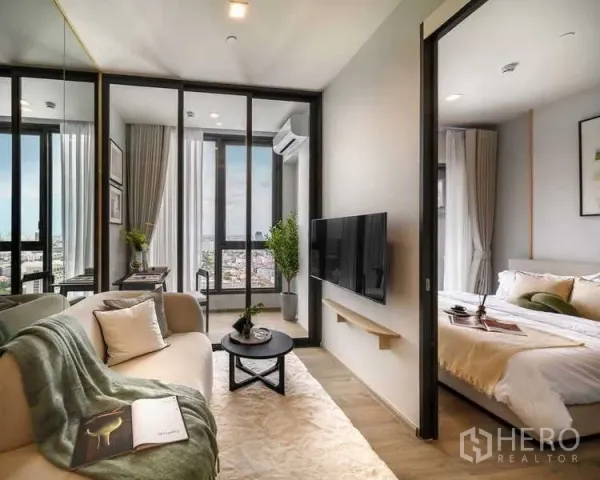 公寓 出租在Chatuchak, Bangkok - 采光充足的客厅，玻璃隔断与卧室相连，挂墙电视，通向观景阳台俯瞰城市。