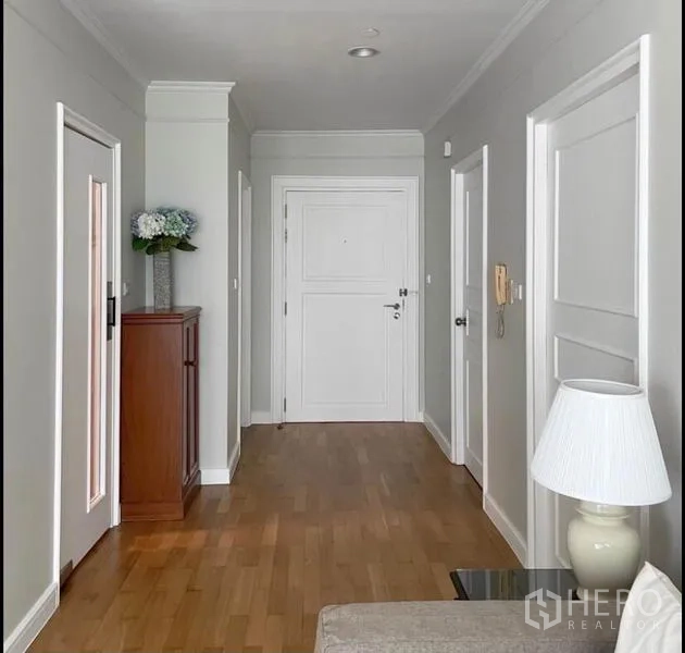 Condominium for rent in Sathon, Bangkok - Entrance hallway with wooden floors, white doors and a slim storage cabinet.