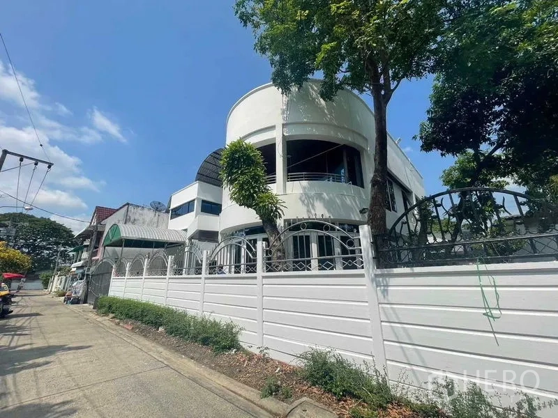 带办公室的家 出售 - 街景视角，弧形现代外立面，高白色围墙与成树。