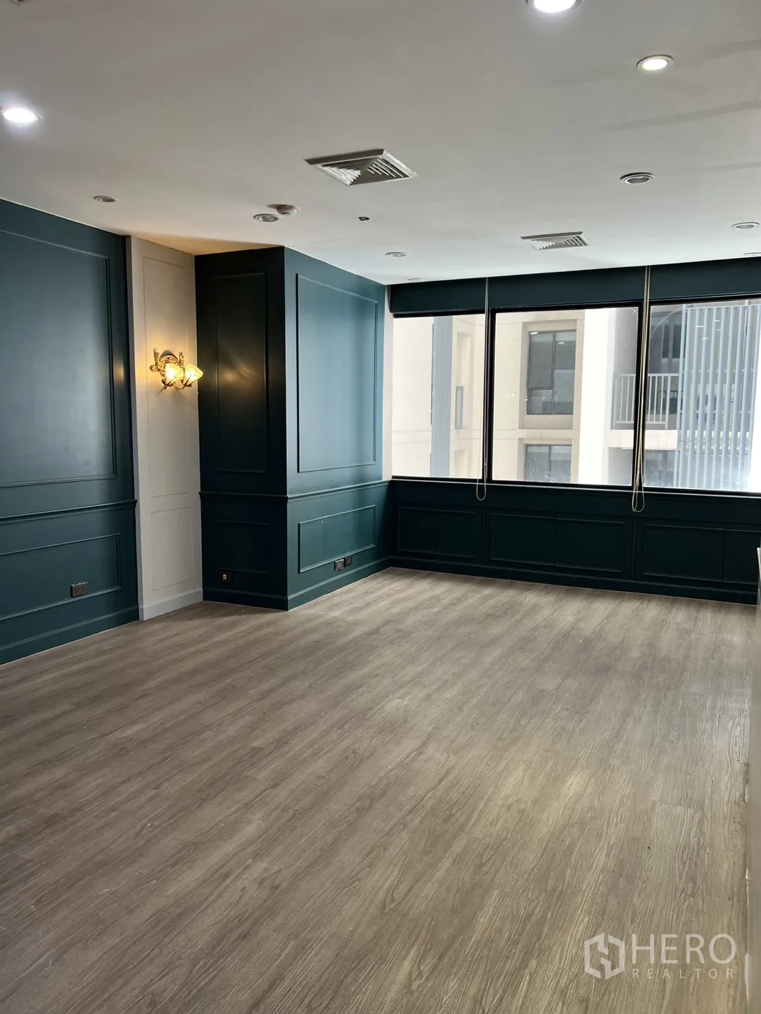 Office Space for rent in Watthana, Bangkok - Corner room with teal wall panels and large windows.