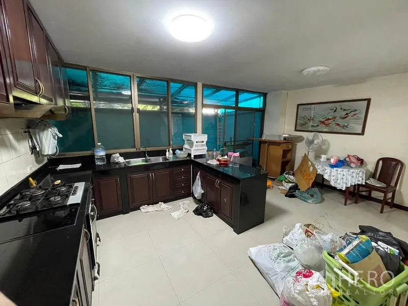 Home Office for rent in Watthana, Bangkok - L-shaped kitchen with dark wood cabinets, black countertops and large windows.