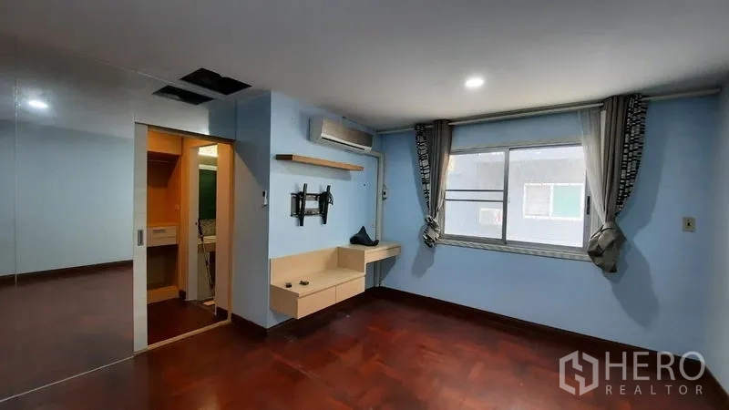 Townhouse for rent or sale in Suan Luang, Bangkok - Air-conditioned bedroom with window, built-in desk, and ensuite access.