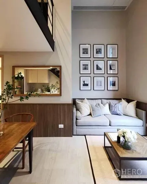 Condominium for rent in Bang Rak, Bangkok - Open-plan living and dining area with high ceiling, wall mirror and mezzanine railing.