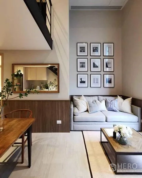 Condominium for rent in Bang Rak, Bangkok - Open-plan living and dining area with high ceiling, wall mirror and mezzanine railing.