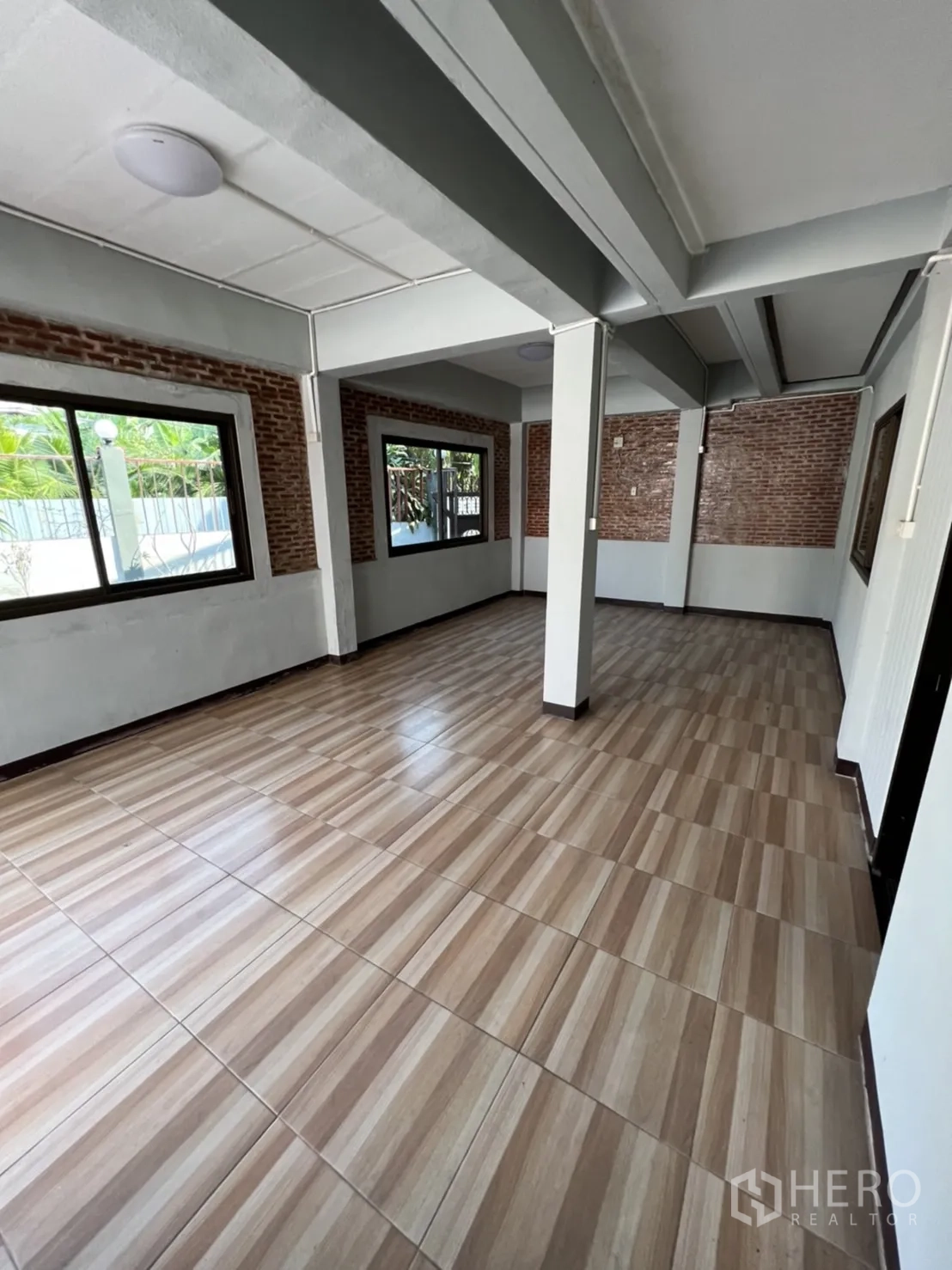 带办公室的家 出租在Watthana, Bangkok - 一层开放空间，设立柱、裸砖装饰墙与大窗户。