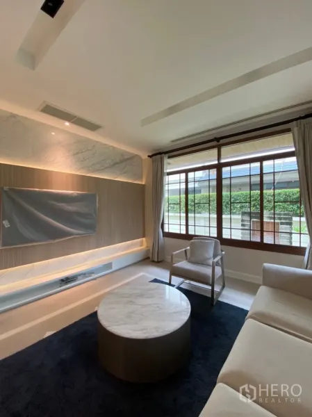 Detached House for rent in Bang Phli, Samut Prakan - Cozy living room with built-in TV wall, cove lighting, sofa and marble coffee table.
