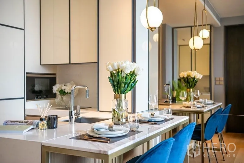 Condominium for rent or sale in Khlong Toei, Bangkok - Dining peninsula with sink, flowers and place settings under globe pendants.