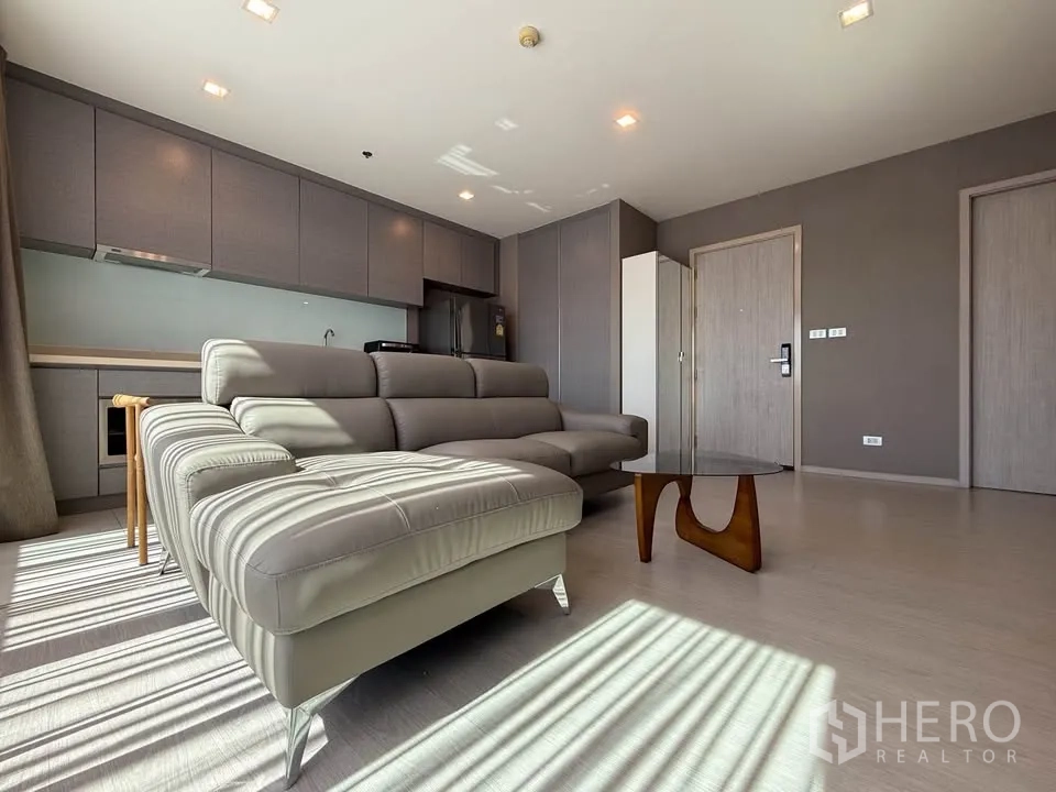 公寓 for rent in Khlong Toei, Bangkok - 明亮客厅配转角沙发、茶几和整墙厨房柜体。