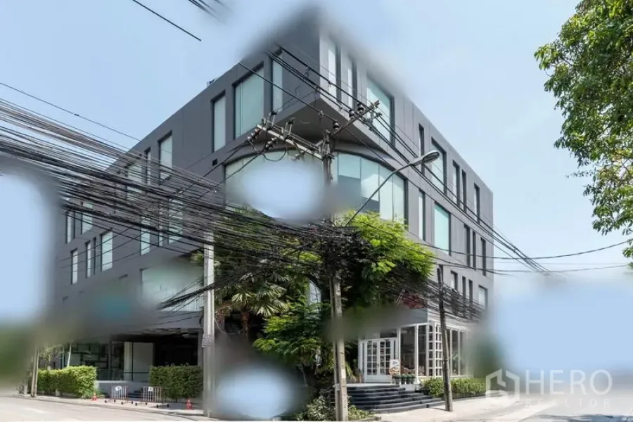 零售空间 出租在Watthana, Bangkok - 曼谷瓦他那区现代多层商业楼外观，大窗与绿化角落。