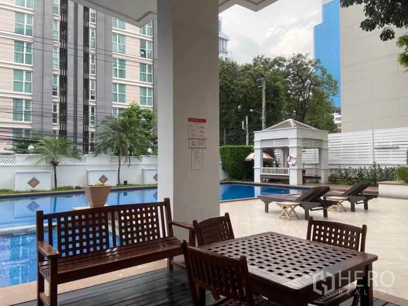 公寓 出租在Watthana, Bangkok - 公区设施含室外泳池、躺椅与带顶休闲座位区。