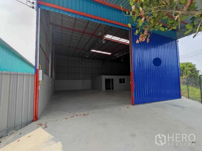 货栈 出租在Pak Kret, Nonthaburi - 高挑仓库，蓝色大型推拉门，混凝土前场，内设办公室。