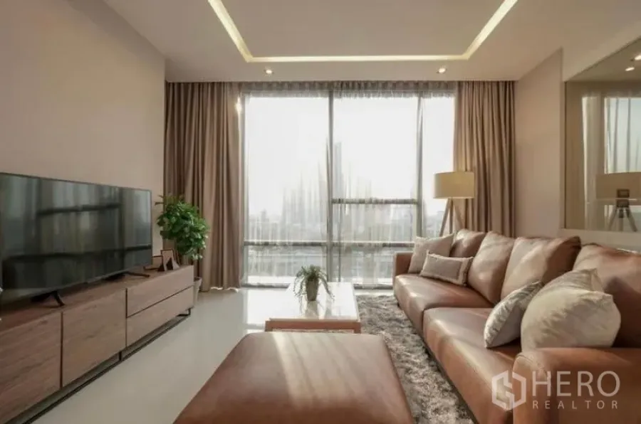 คอนโด ให้เช่าในSathon, Bangkok - ห้องนั่งเล่นรับแสงธรรมชาติ ผนังกระจกเต็มบาน โซฟาหนังและชั้นวางทีวีพร้อมวิวเมือง