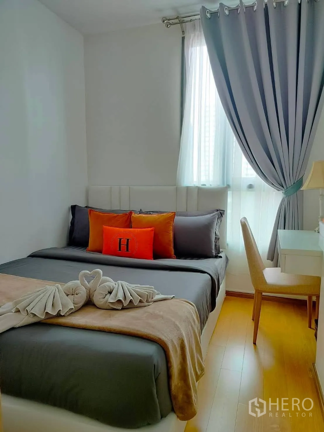 Condominium for rent in Watthana, Bangkok - Cozy bedroom with double bed, desk, and floor-to-ceiling curtains by a bright window.