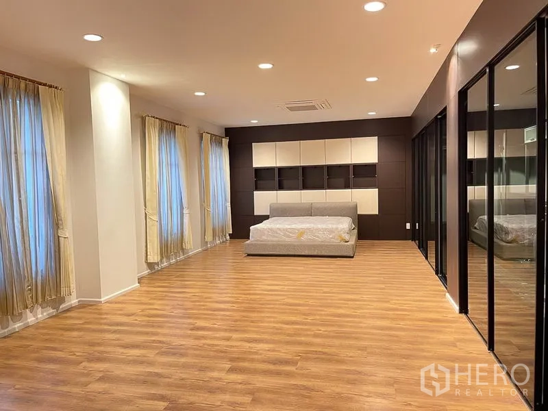 Townhouse for rent in Yan Nawa, Bangkok - Expansive bedroom with multiple windows, recessed lights and mirrored sliding-door wardrobes.