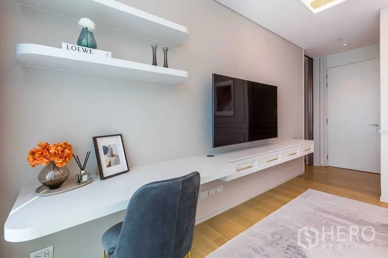 Condominium for sale in Pathum Wan, Bangkok - Workstation with floating desk, shelves and wall-mounted TV in a minimalist room