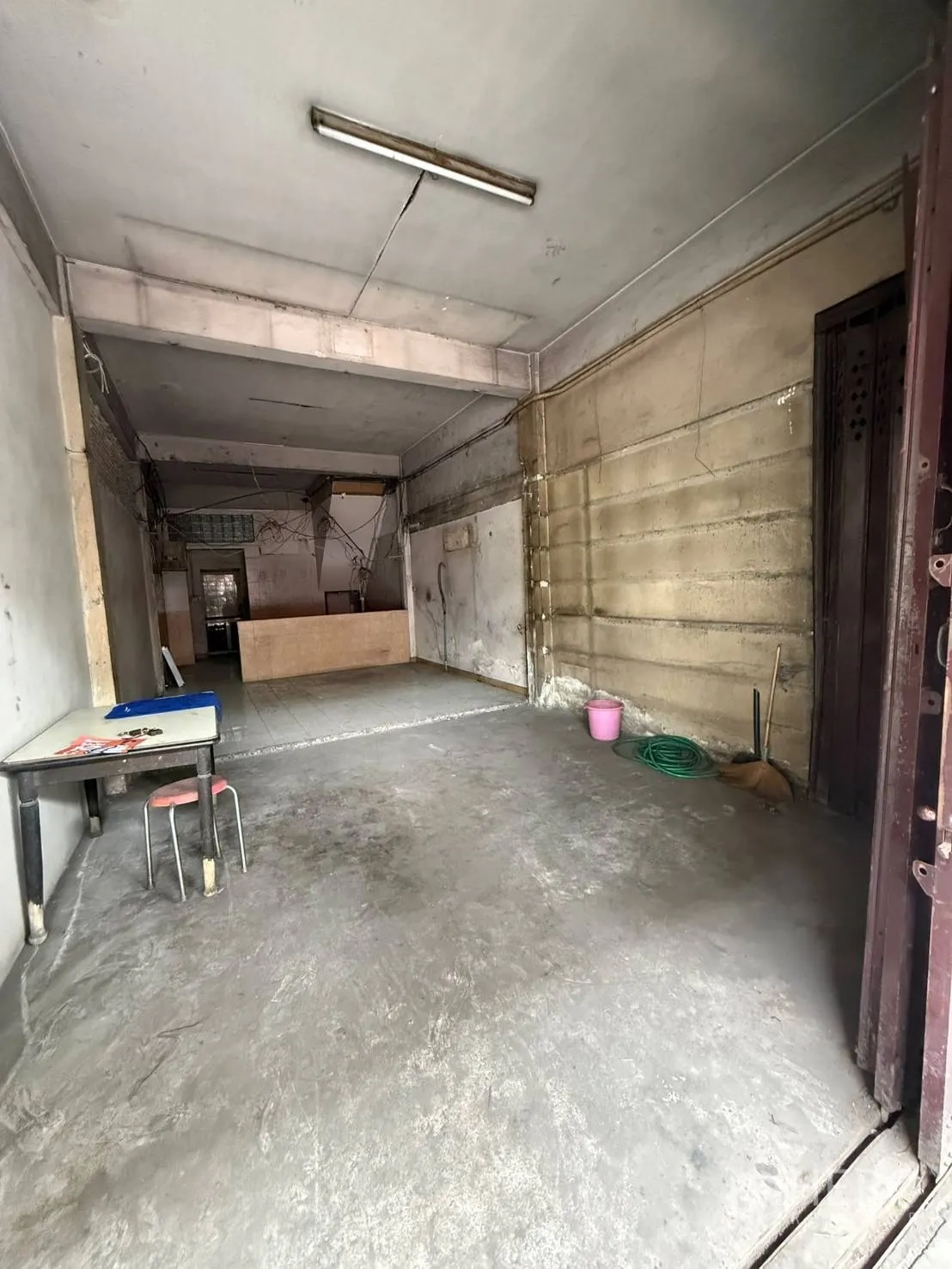 Shophouse for rent in Khlong Toei, Bangkok - View of the deep ground-floor hall with a small table and cleaning tools along the wall.
