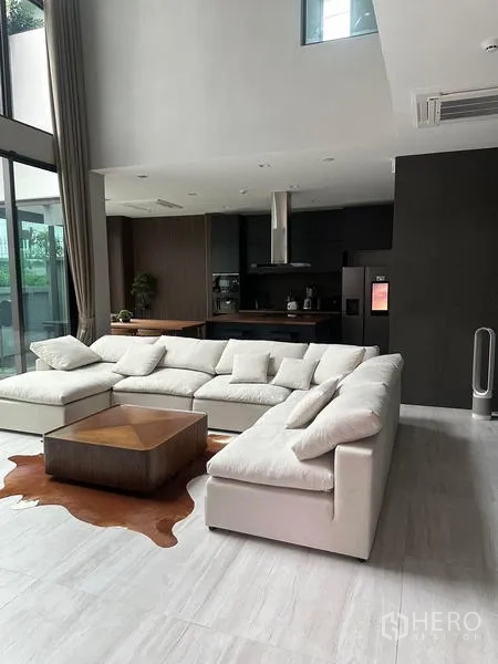Detached House for rent in Saphan Sung, Bangkok - Double-height living room with white sectional and kitchen beyond.