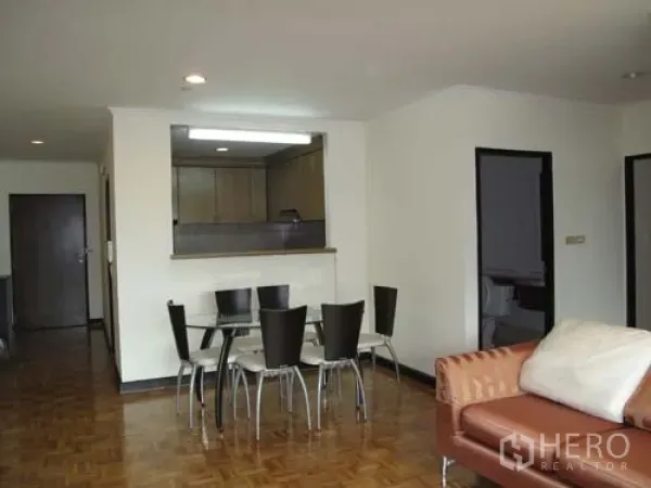 Condominium for rent in Sathon, Bangkok - Bright living and dining area with glass table, sofa and pass-through to the kitchen over parquet floors.
