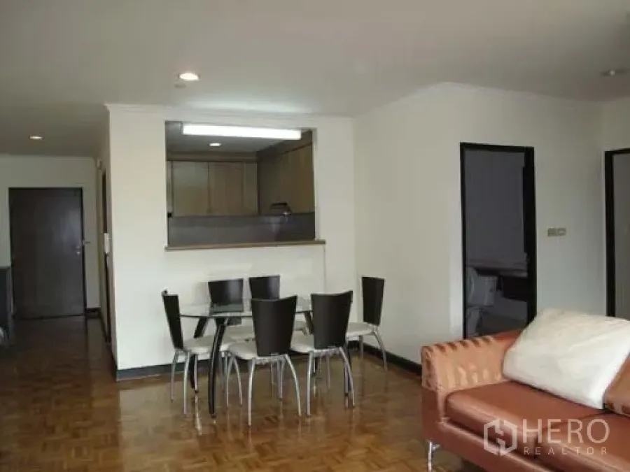 Condominium for rent in Sathon, Bangkok - Bright living and dining area with glass table, sofa and pass-through to the kitchen over parquet floors.