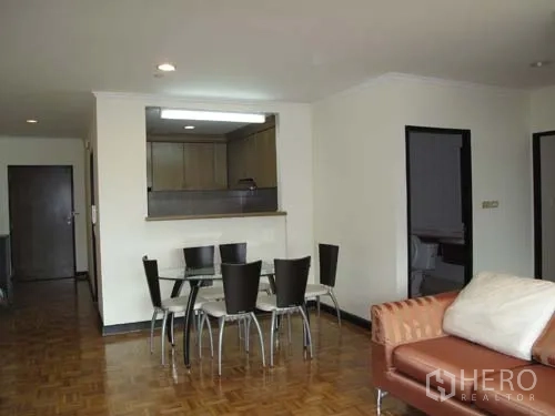 Condominium for rent in Sathon, Bangkok - Bright living and dining area with glass table, sofa and pass-through to the kitchen over parquet floors.
