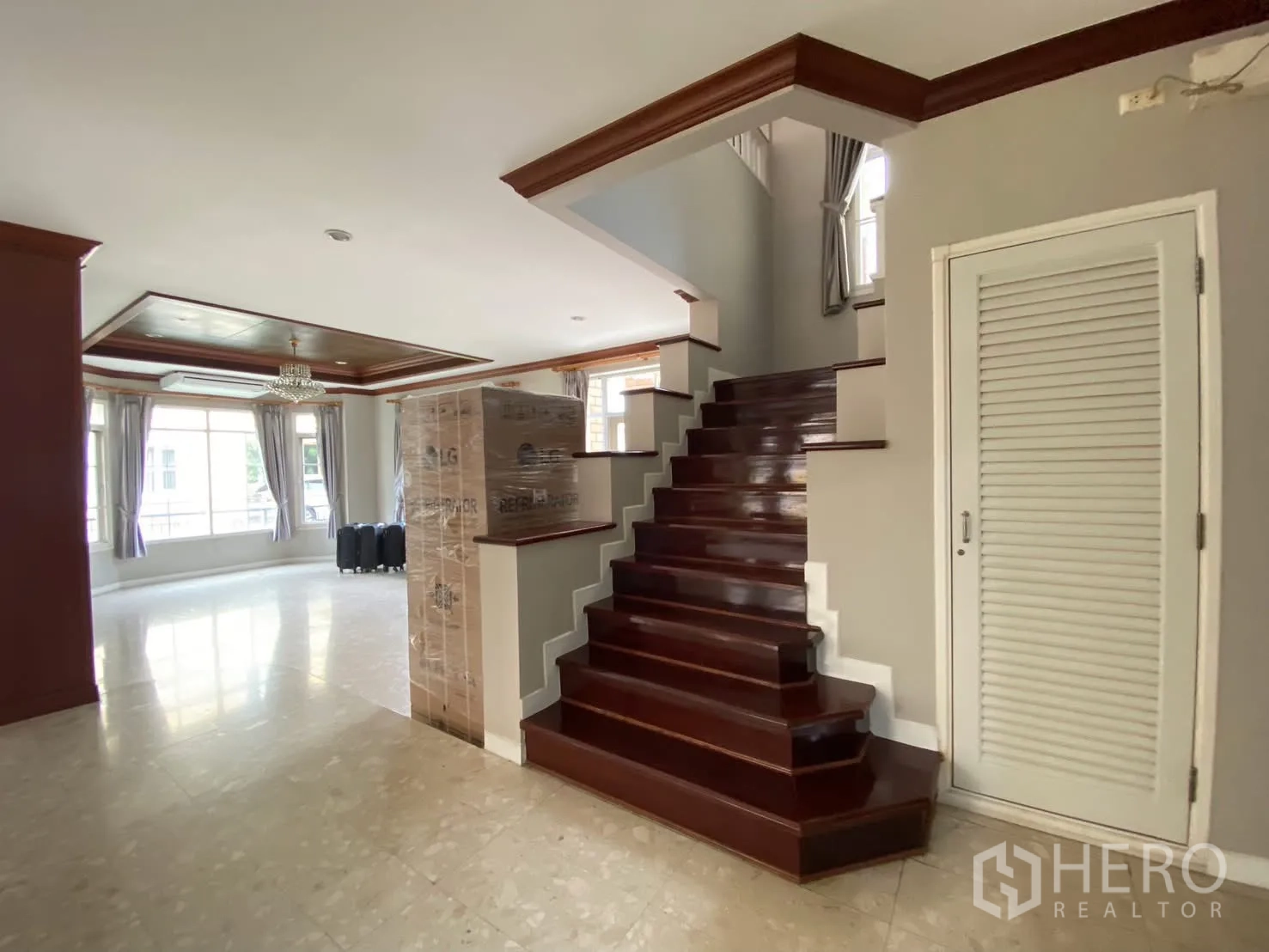 Detached House for rent in Phra Khanong, Bangkok - Ground-floor hall with glossy wooden stairs, bright open living area, and large windows.