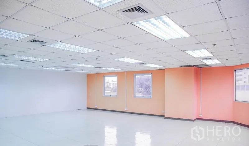 办公空间 出租在Bang Na, Bangkok - 转角办公室，橙色强调墙、窗口和天花空调出风口。
