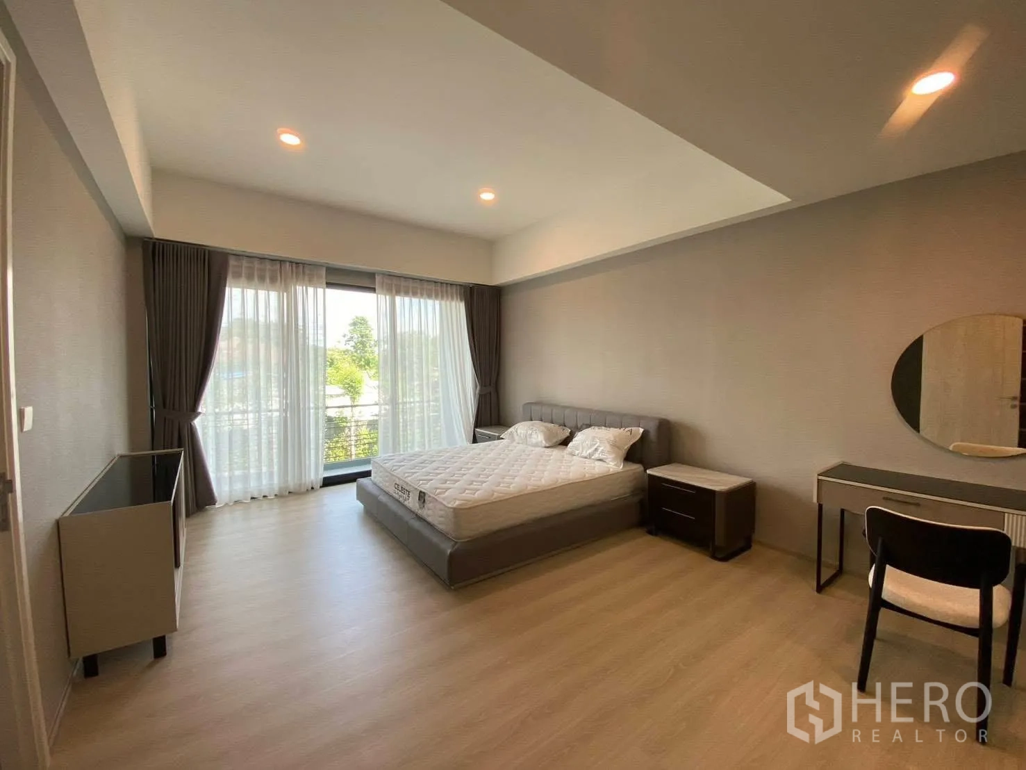 Townhouse for rent in Bang Kapi, Bangkok - Spacious bedroom with balcony access, large windows, bed, desk, and soft lighting.