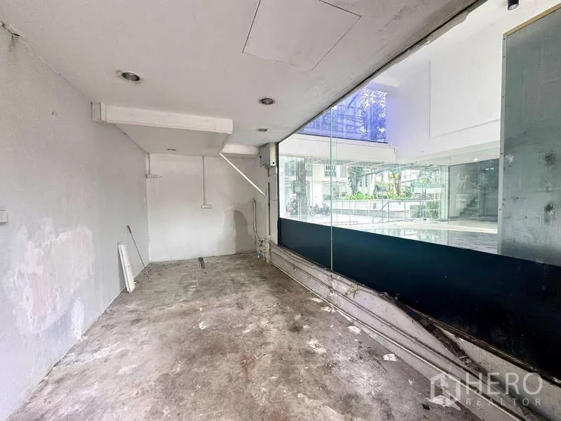 零售空间 出租在Bang Rak, Bangkok - 店内后勤与储物区，水泥地面及玻璃隔断。