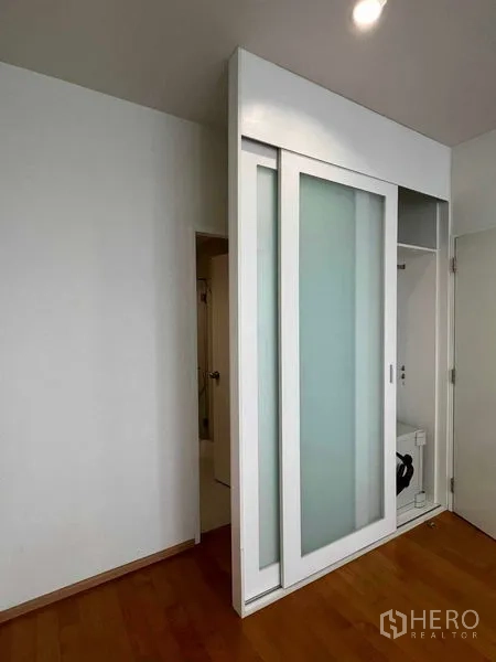 Condominium for rent in Ratchathewi, Bangkok - Sliding frosted-glass door concealing storage and utility space.