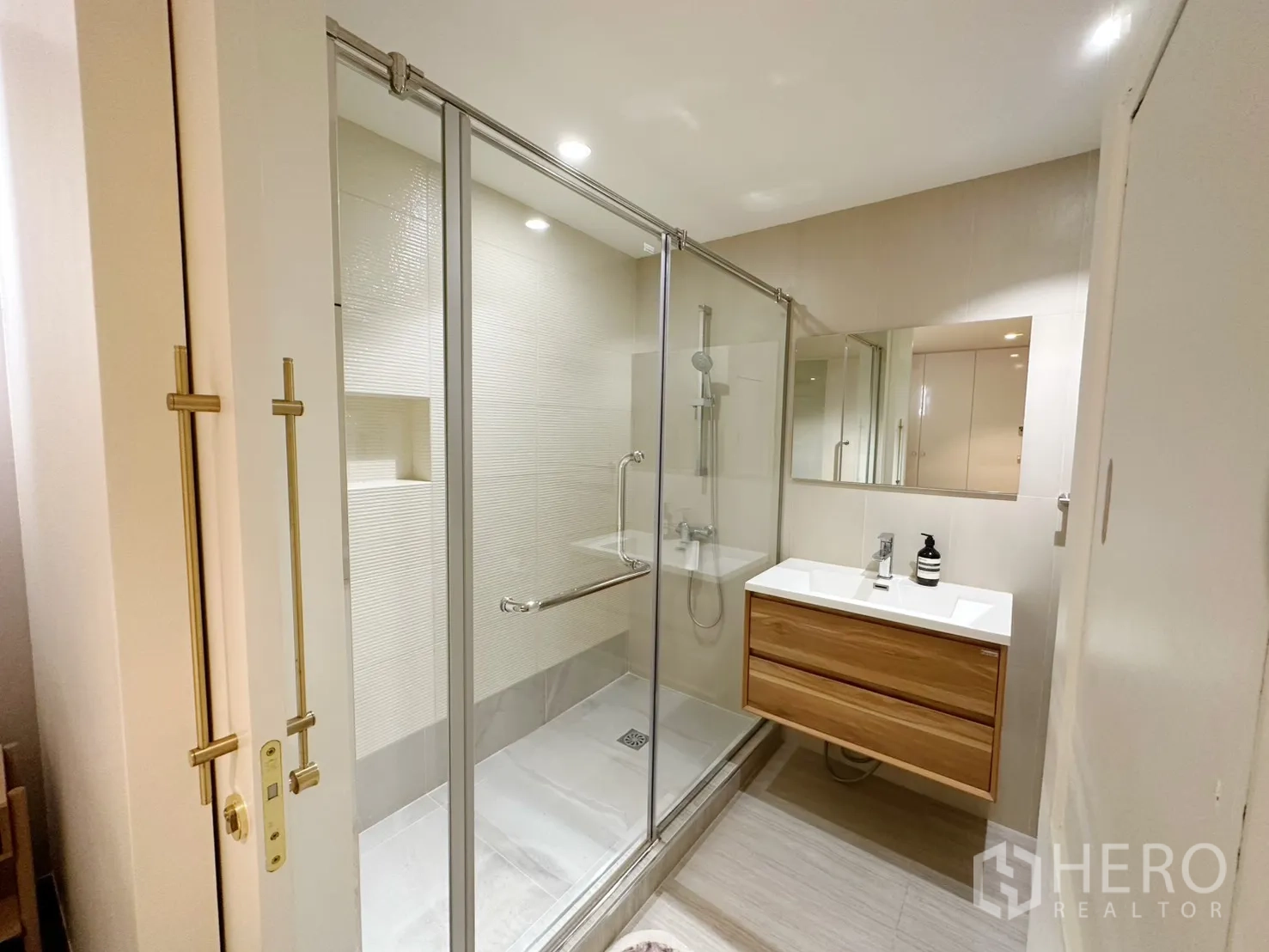 Condominium for rent or sale in Watthana, Bangkok - Bathroom with glass-enclosed shower and floating wood vanity.