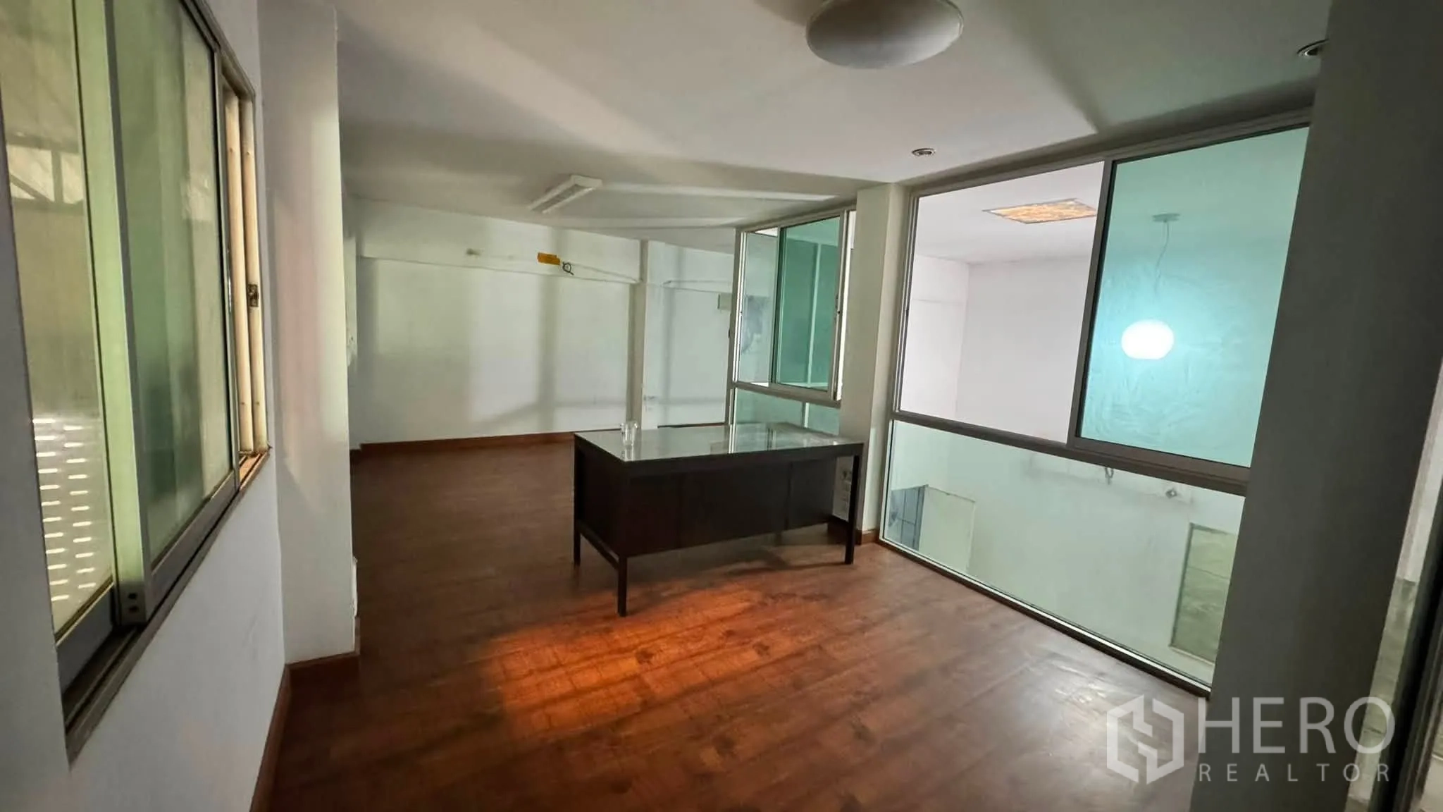 โกดัง for rent in Bang Khen, Bangkok - ออฟฟิศชั้นลอยพร้อมหน้าต่างกระจกและโต๊ะทำงานมองลงสู่พื้นที่โกดัง.