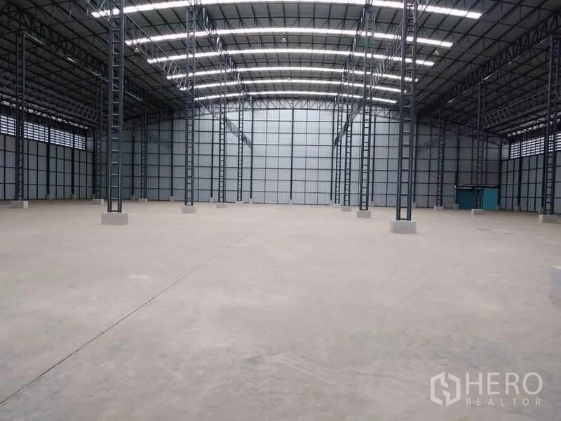 Factory for rent in Mueang Samut Prakan, Samut Prakan - Central bay of the warehouse facing the far wall under rows of skylights and LED strips.