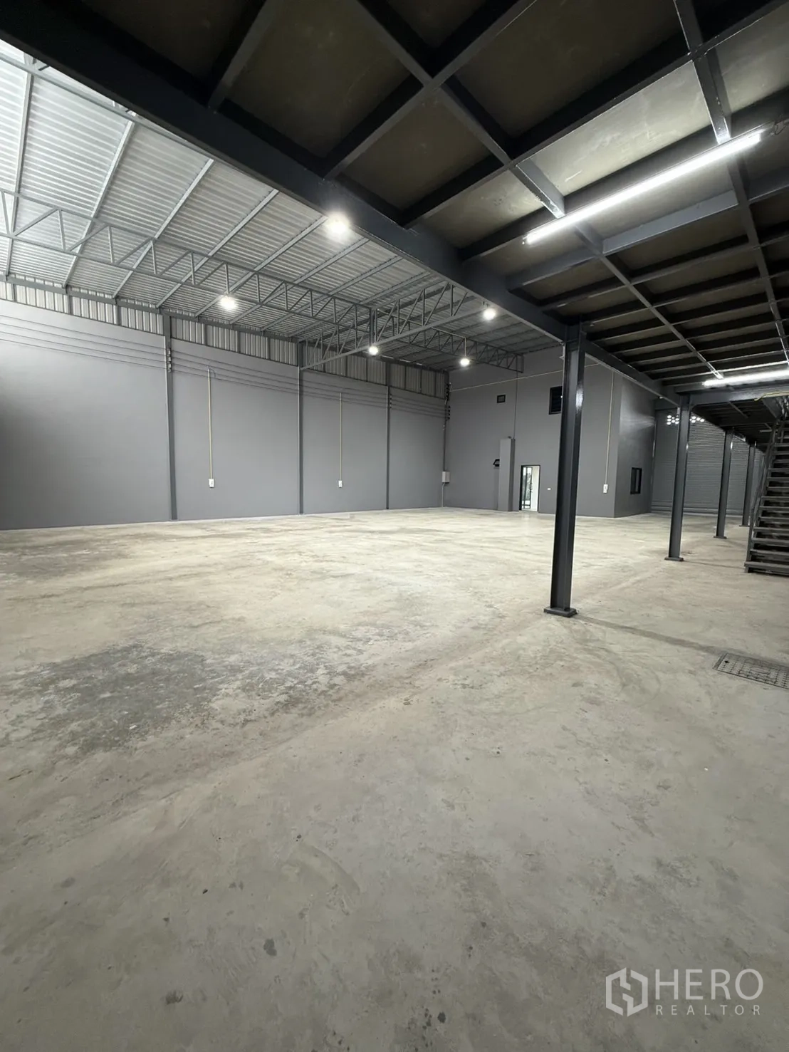 Warehouse for rent in Lam Luk Ka, Pathum Thani - Open warehouse floor with mezzanine and bright lighting.
