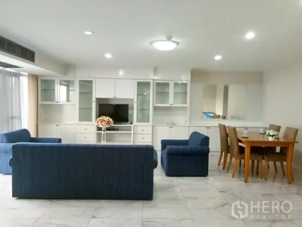 Condominium for rent in Watthana, Bangkok - Open living and dining area with white cabinetry, blue sofas and recessed lighting.