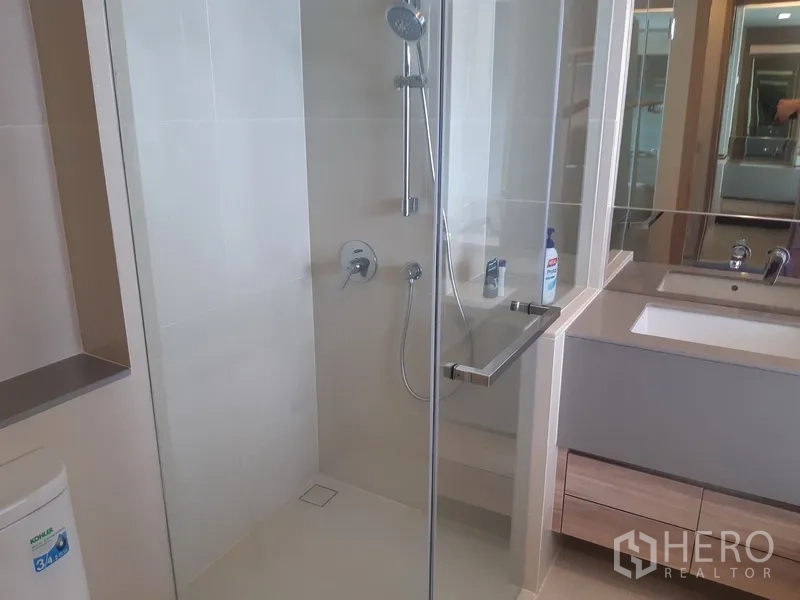 公寓 出租或出售在Watthana, Bangkok - 现代浴室设玻璃淋浴间、手持花洒与宽大洗手台。