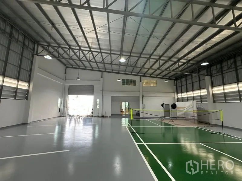 Warehouse for sale in Pathum Thani - Warehouse interior showing roller door, ventilation windows and sports court lines.