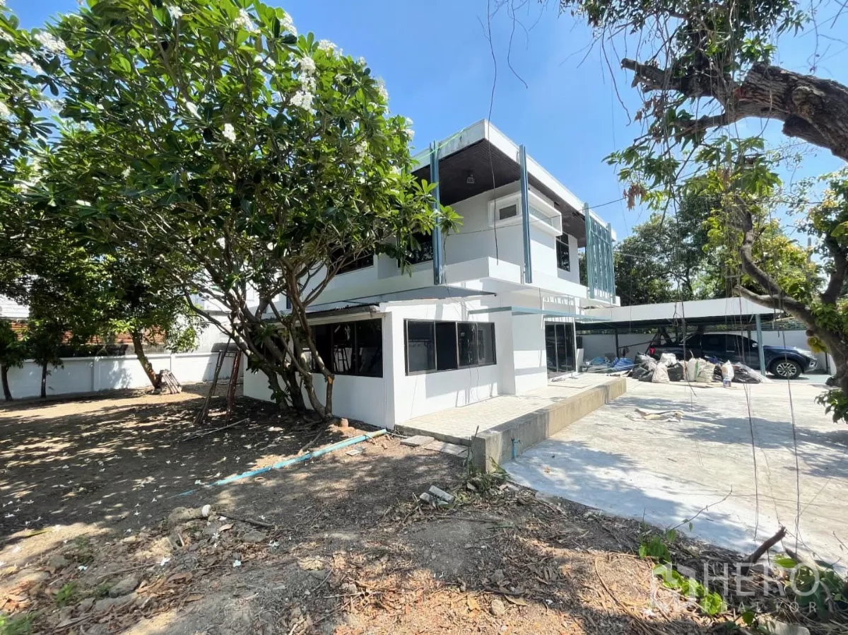 Home Office for rent in Din Daeng, Bangkok - Rear exterior of the white two‑storey house with paved patio, garden and on‑site parking.
