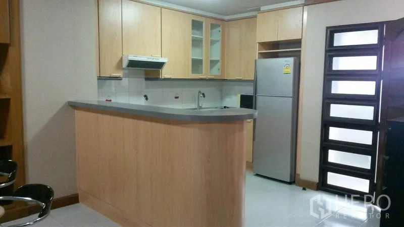 Condominium for rent in Watthana, Bangkok - Light wood kitchen with breakfast bar, cabinets, range hood and stainless refrigerator.