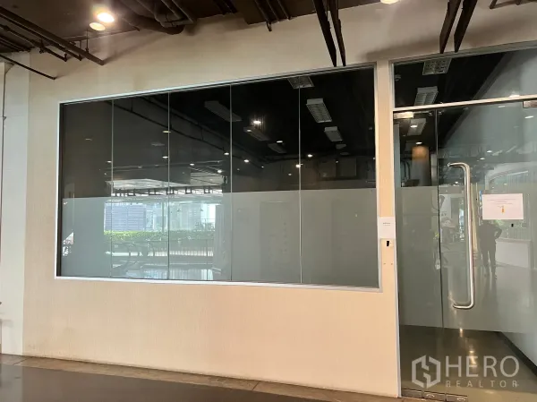 Retail Space for rent - Retail unit exterior showing large glazed façade and stainless pull-handle door along the corridor.