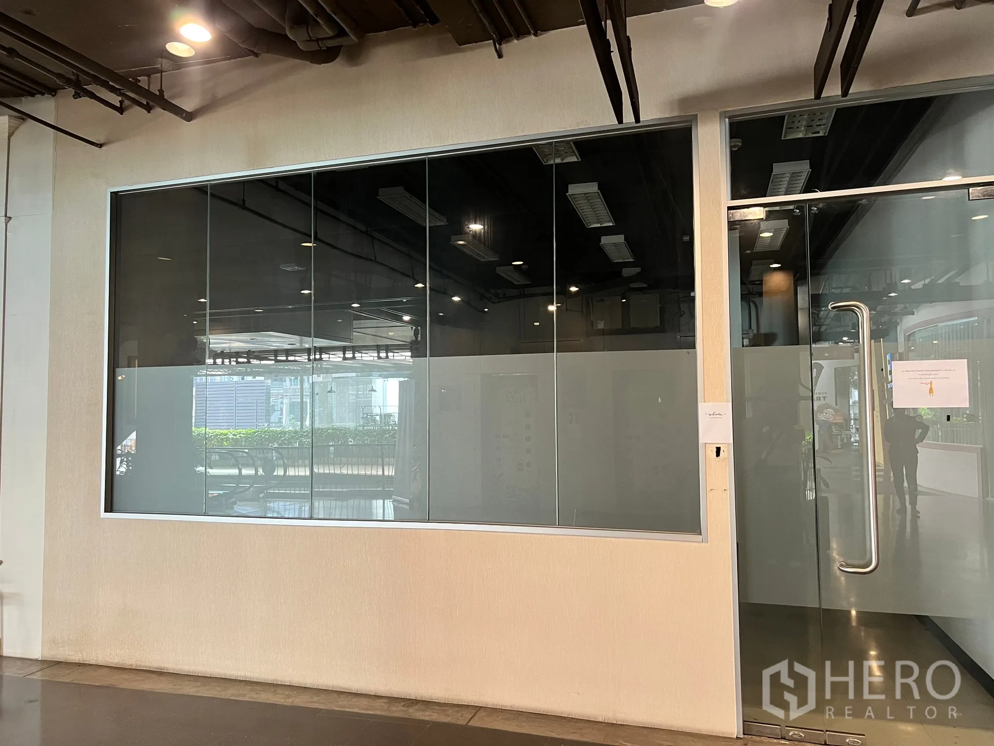 Retail Space for rent - Retail unit exterior showing large glazed façade and stainless pull-handle door along the corridor.