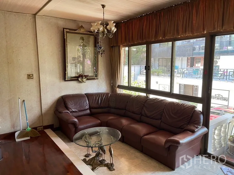 Home Office for rent in Watthana, Bangkok - Corner lounge with leather sectional sofa, chandelier and large windows.