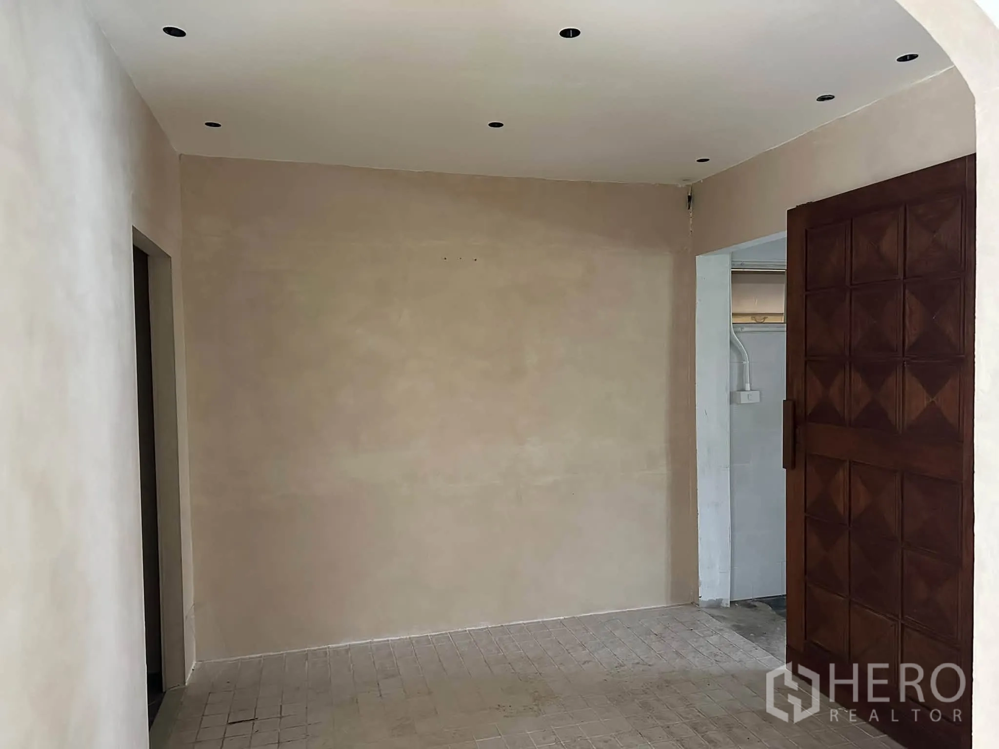 พื้นที่ขายของ for rent in Khlong Toei, Bangkok - โถงเล็กผนังลายปูนและประตูไม้ลายเรขาคณิตบานใหญ่