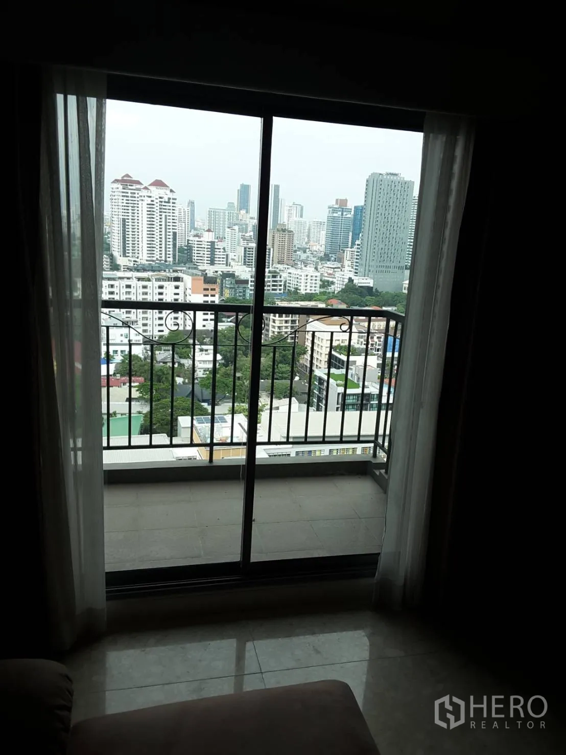 Condominium for rent in Khlong Toei, Bangkok - Sliding glass door opening to a balcony with expansive city skyline views.