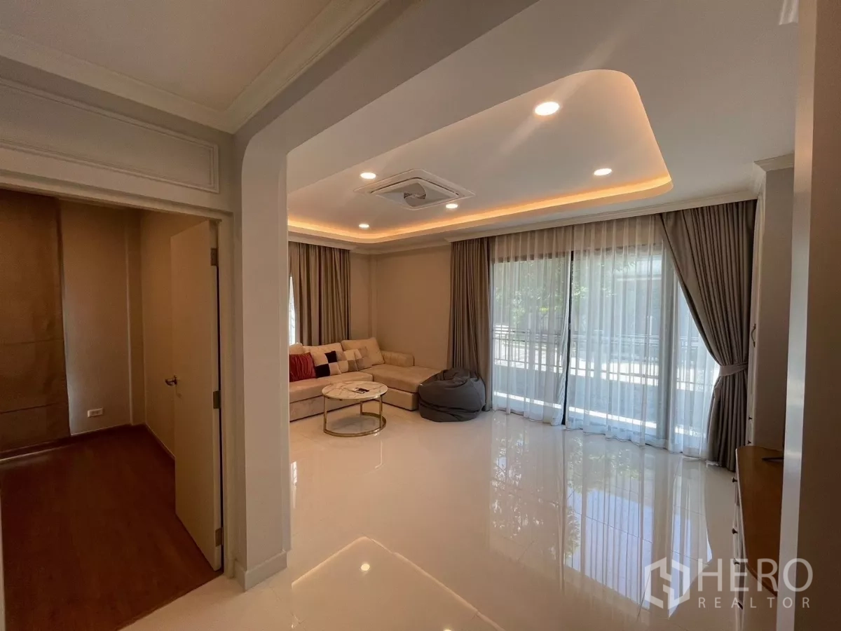 独立式住宅 出租在Bang Phli, Samut Prakan - 舒适起居室，转角沙发、茶几与落地纱帘。
