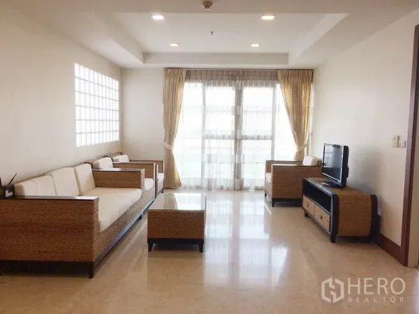 公寓 出租在Khlong Toei, Bangkok - 采光充足的客厅，藤编沙发、电视柜与落地窗。