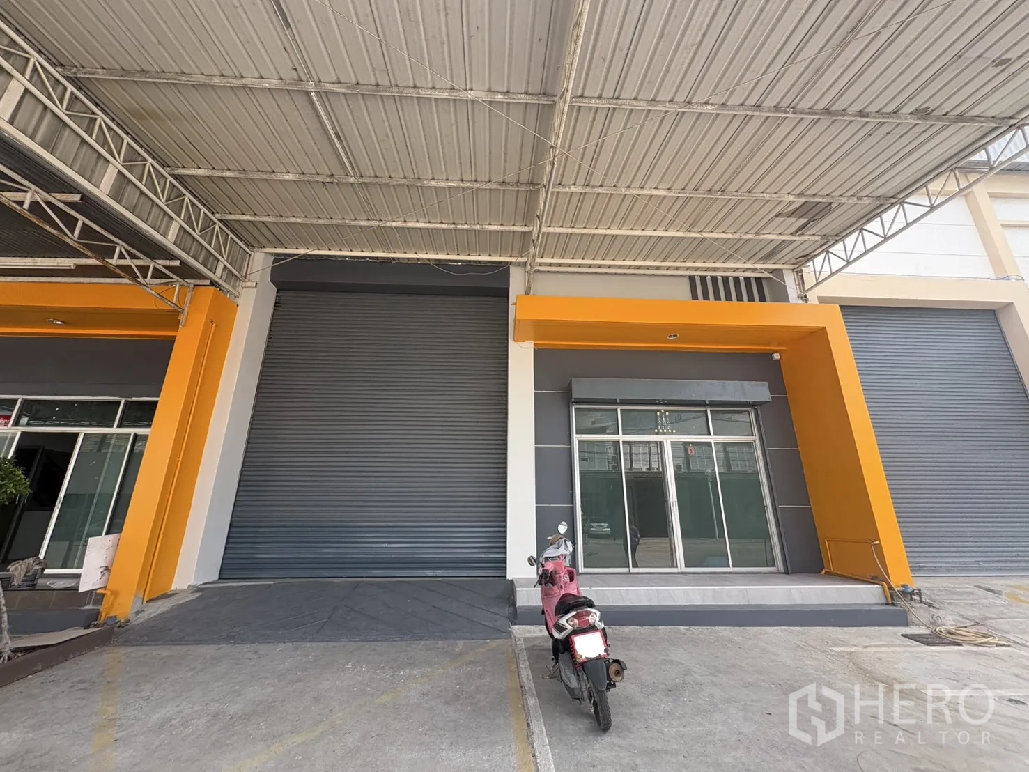 Factory for rent in Phra Samut Chedi, Samut Prakan - Factory frontage with large roller shutters, glass-front office and a covered loading bay.