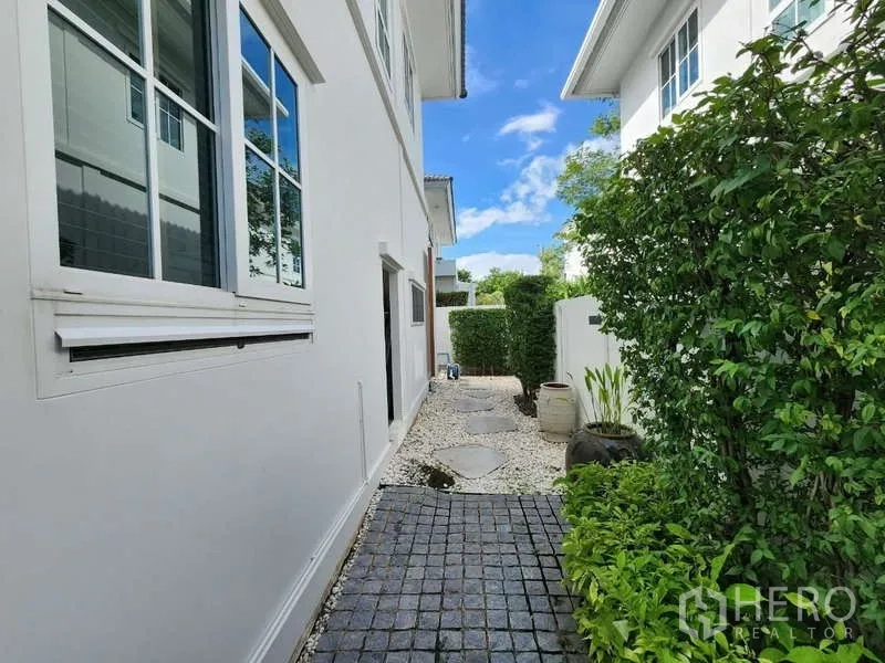 Detached House for rent or sale in Bang Phli, Samut Prakan - Side walkway along the detached house with pebble landscaping and greenery.