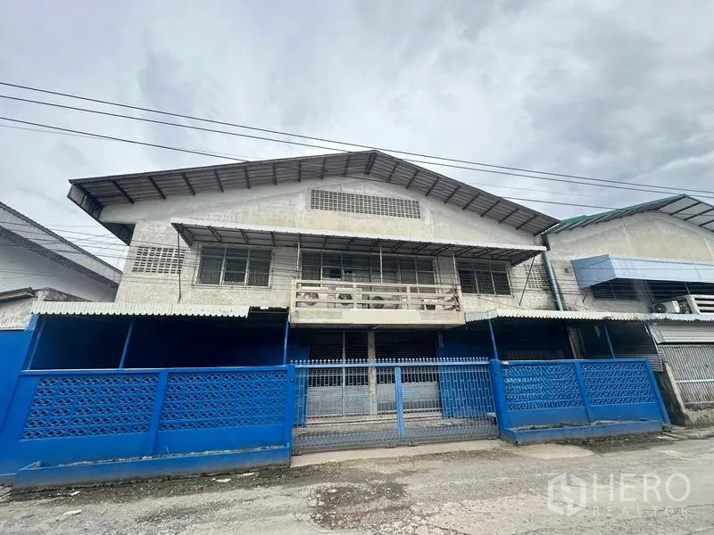 工厂 出租在Lam Luk Ka, Pathum Thani - 两层工厂外立面，配蓝色大门与遮雨棚