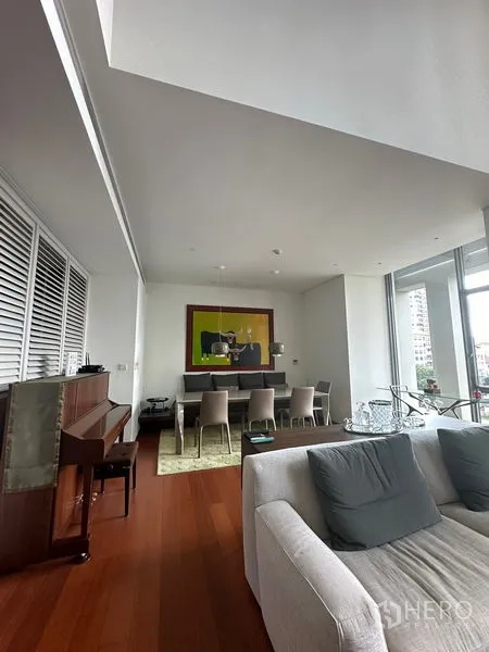 Condominium for rent or sale in Sathon, Bangkok - Open-plan lounge and dining with wide windows, sofa, artwork, and wood floors.