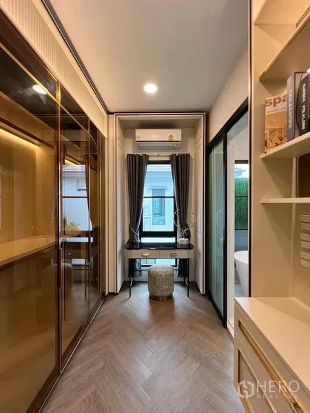 Detached House for rent or sale in Saphan Sung, Bangkok - Compact home office corridor with built-in shelving, glass wardrobe and a window desk.